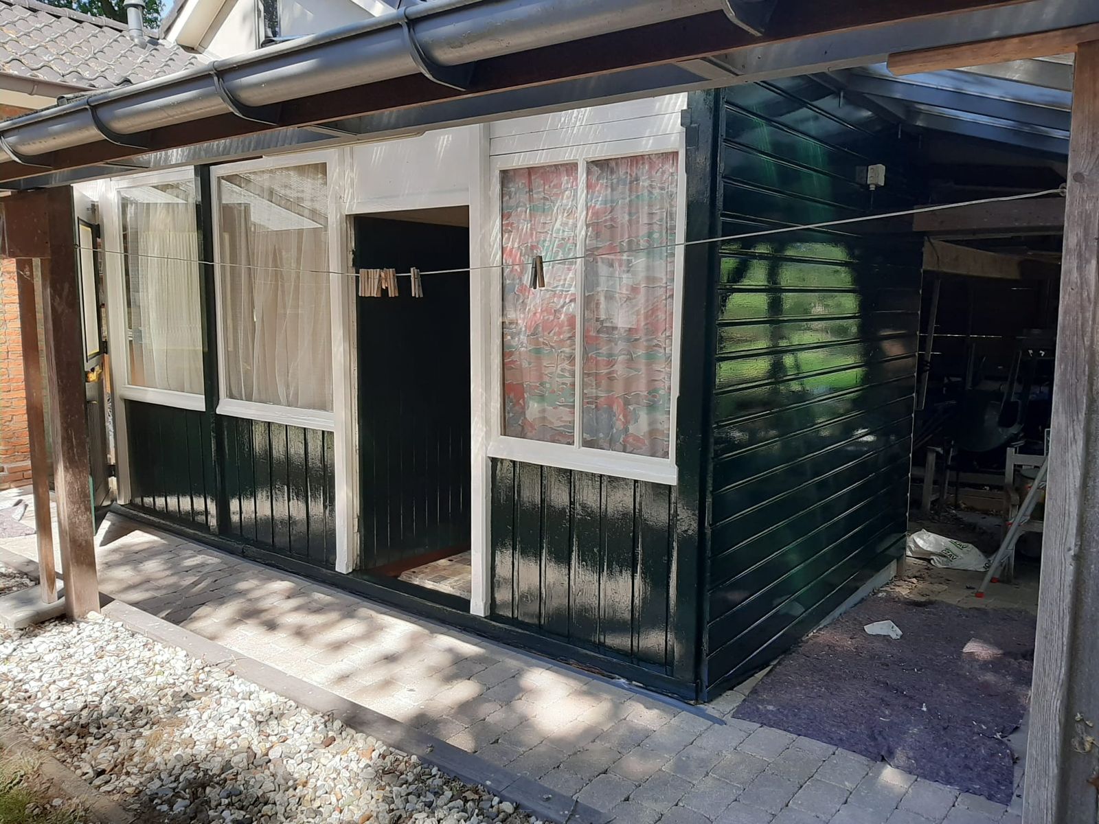 Donkergroen geschilderde schuur met witte kozijnen