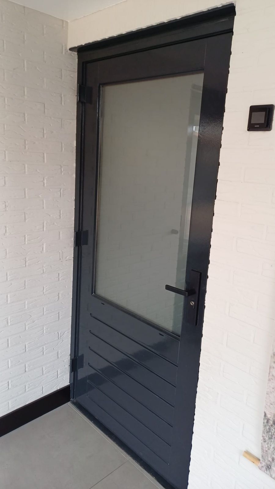 Antraciet deur met glas in een witte gevel