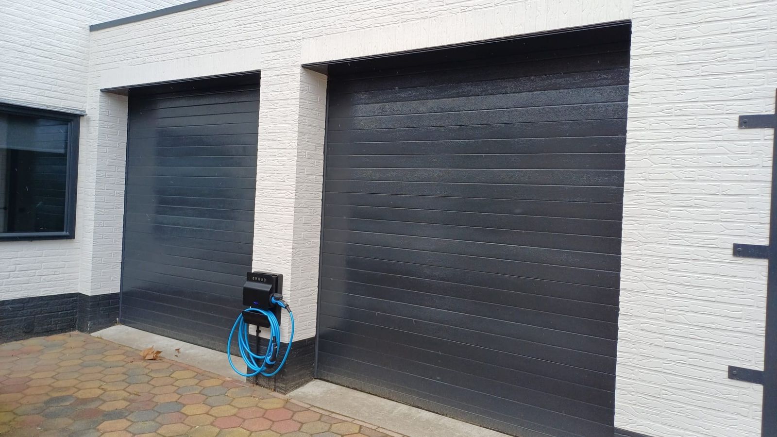 Twee zwarte garagedeuren in een witte gevel