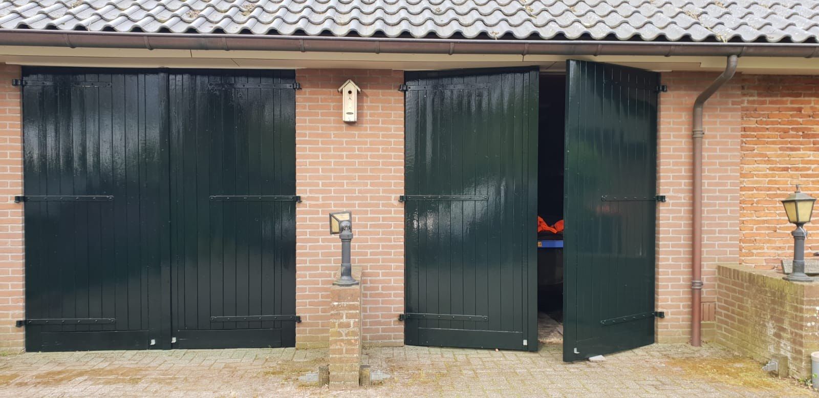Donkergroene luiken en deuren in een bakstenen muur