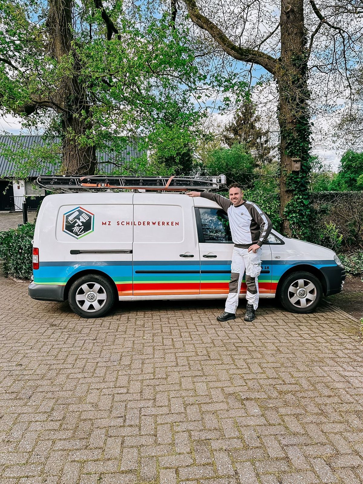 Mathieu Zandbergen in schilderskleding naast de bus van MZ Schilderwerken