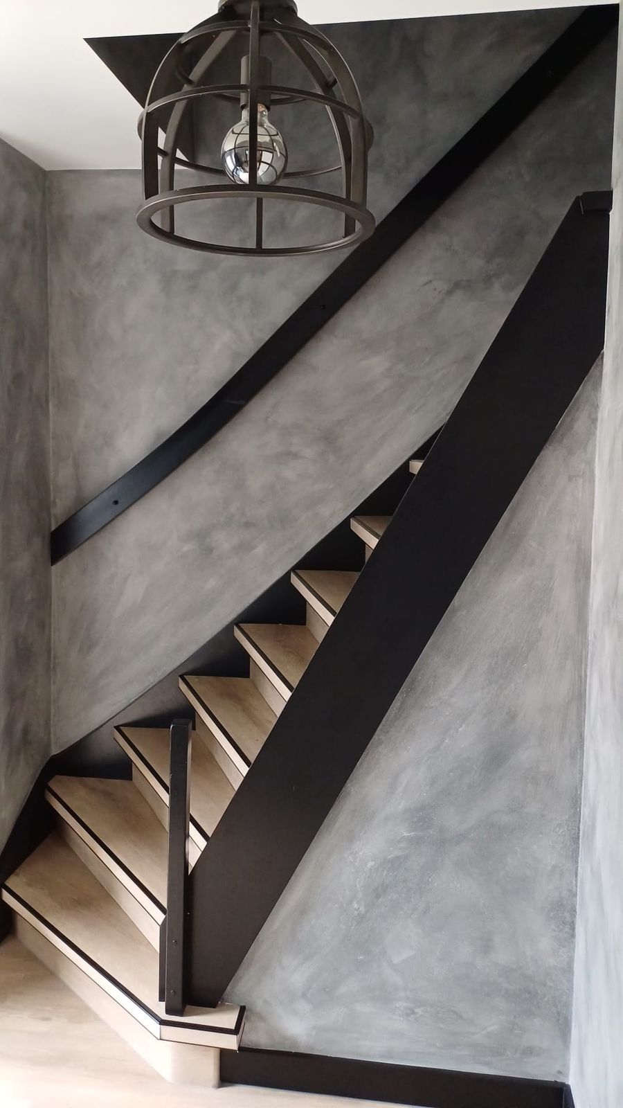 Zwarte traptrede en boom langs een betonlook wand