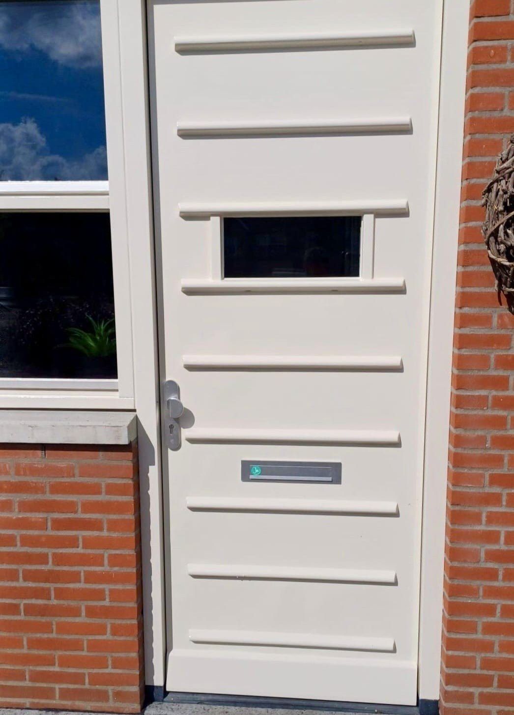 Crèmekleurige paneeldeur in een bakstenen gevel