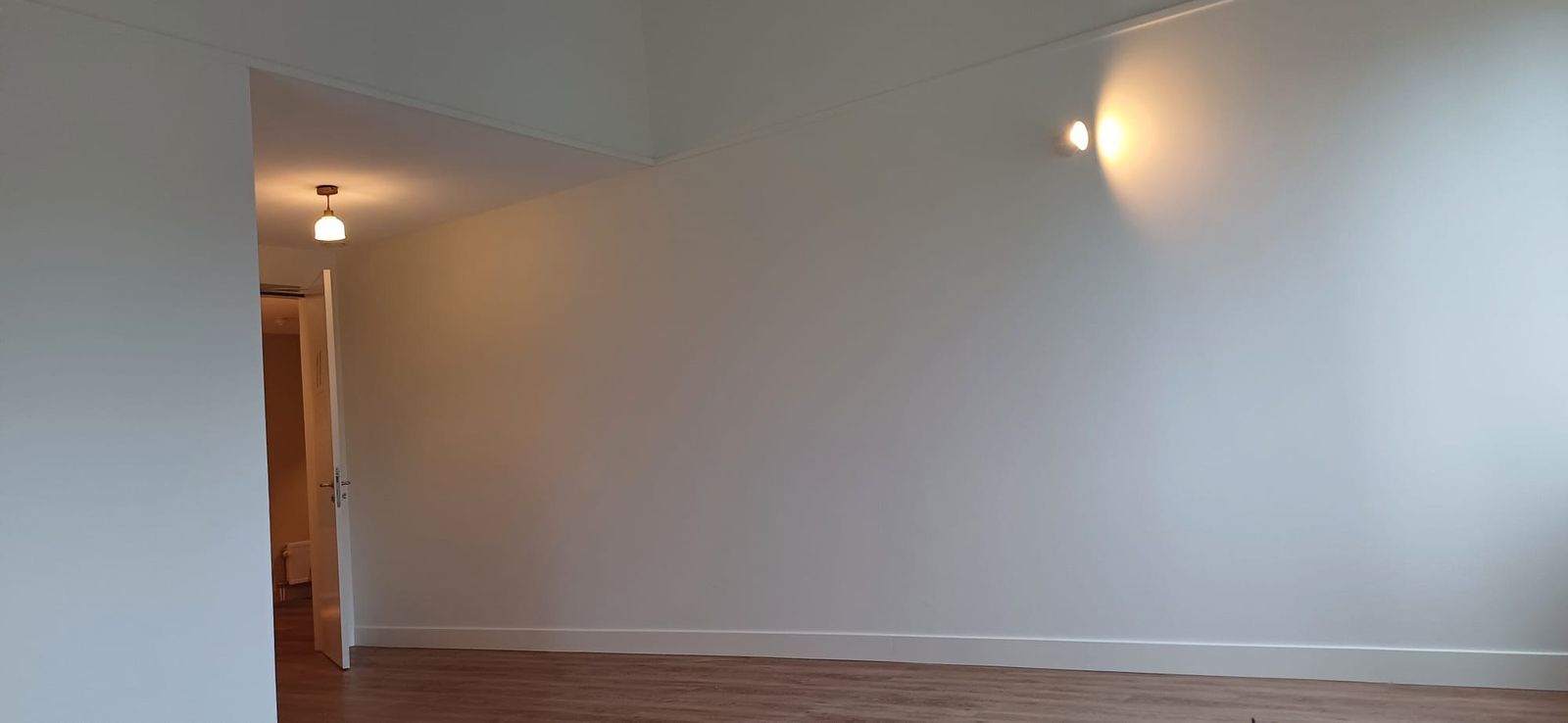 Witte zolderkamer met wandlamp